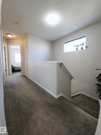 Hallway with plenty of natural light, carpet floors, a textured ceiling, and an upstairs landing - 