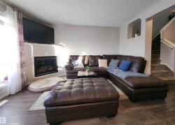 Living room featuring wood finished floors, a textured ceiling, a glass covered fireplace, and stairs - 