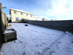 Yard layered in snow featuring a fenced backyard, an outdoor fire pit, and a wooden deck - 