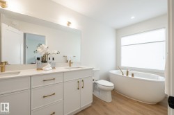 Full bath featuring double vanity, a freestanding bath, and light wood-type flooring - 
