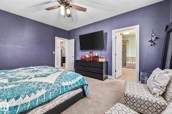 Bedroom featuring light carpet, a ceiling fan, and ensuite bath - 