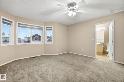Unfurnished bedroom featuring a textured ceiling, light carpet, ceiling fan, ensuite bathroom, and attic access - 3316 24 Avenue, Edmonton, AB - Indoor Photo Showing Other Room