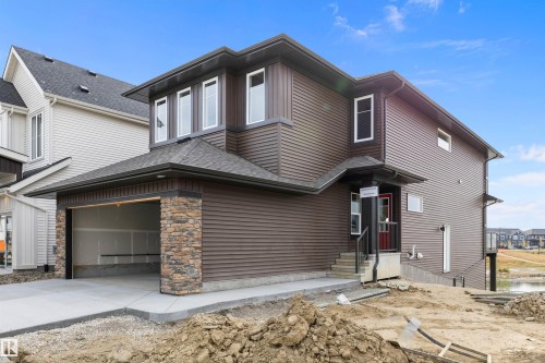 View of front of property with a garage, a shingled roof, stone siding, and concrete driveway - 4544 Kinsella Link, Edmonton, AB - Outdoor