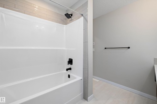 Bathroom with washtub / shower combination, vanity, and a textured ceiling - 4544 Kinsella Link, Edmonton, AB - Indoor Photo Showing Bathroom