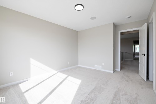 Unfurnished bedroom featuring light carpet and baseboards - 4544 Kinsella Link, Edmonton, AB - Indoor Photo Showing Other Room