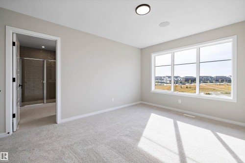 Unfurnished bedroom featuring light colored carpet, a residential view, and ensuite bath - 4544 Kinsella Link, Edmonton, AB - Indoor Photo Showing Other Room