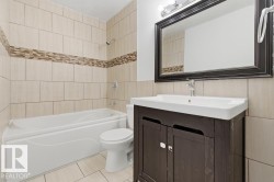 Full bathroom featuring vanity,  shower combination, tile walls, and light tile patterned floors - 