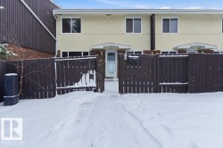 Snow covered property with a fenced front yard and stucco siding - 