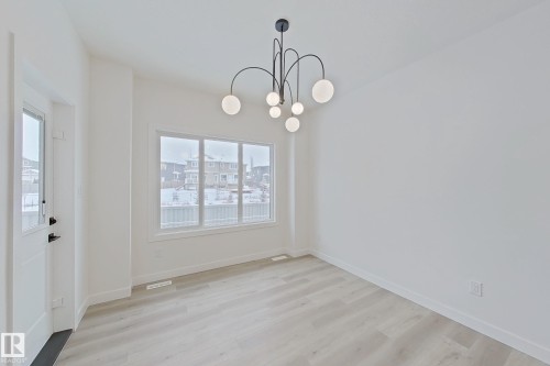 Unfurnished dining area featuring light wood finished floors and a chandelier - 3158 Magpie Way, Edmonton, AB - Indoor Photo Showing Other Room