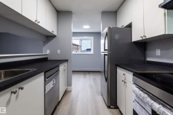 Kitchen featuring dark countertops, appliances with stainless steel finishes, white cabinetry, light wood-type flooring, and range hood - 