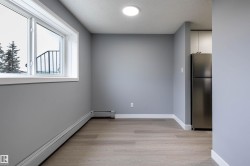 Unfurnished room with baseboard heating, light wood-style flooring, a textured ceiling, and a baseboard radiator - 
