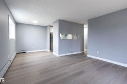 Unfurnished living room with light wood-style flooring, a textured ceiling, and a baseboard heating unit - 