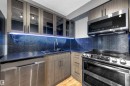 Kitchen with appliances with stainless steel finishes, glass insert cabinets, a textured ceiling, decorative backsplash, and light wood-style flooring - 1702 10150 117 Street, Edmonton, AB  - Indoor Photo Showing Kitchen 