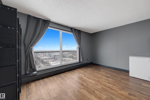 Empty room featuring a baseboard radiator, a textured ceiling, and wood finished floors - 1702 10150 117 Street, Edmonton, AB - Indoor Photo Showing Other Room