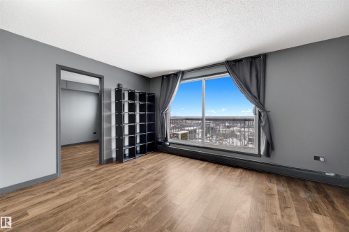 Spare room featuring a textured ceiling, light wood finished floors, and baseboard heating - 1702 10150 117 Street, Edmonton, AB - Indoor Photo Showing Other Room