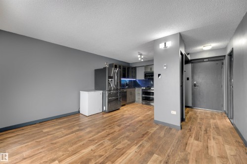 Kitchen with stainless steel appliances, gray cabinets, light wood-style floors, tasteful backsplash, and dark countertops - 1702 10150 117 Street, Edmonton, AB - Indoor Photo Showing Kitchen