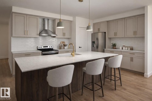 Two tone kitchen featuring stainless steel appliances, light stone countertops, a center island with sink, a kitchen bar, and light wood-style flooring - 10202 92A Avenue, Morinville, AB - Indoor Photo Showing Kitchen With Upgraded Kitchen