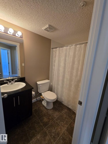 Full bath with curtained shower, vanity, and a textured ceiling - 313 1510 Watt Drive, Edmonton, AB - Indoor Photo Showing Bathroom