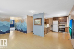 Kitchen featuring stainless steel electric range oven, freestanding refrigerator, light countertops, light wood-style floors, and an accent wall - 