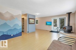 Living room featuring a wood stove, wood finished floors, a textured ceiling, and an accent wall - 
