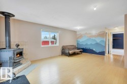 Living area featuring a wood stove, wood finished floors, and an accent wall - 