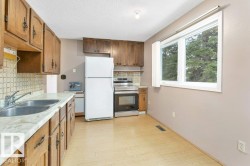 Kitchen with freestanding refrigerator, light countertops, stainless steel electric range oven, brown cabinetry, and light wood-type flooring - 