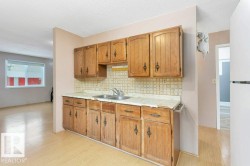 Kitchen featuring light countertops, freestanding refrigerator, light wood-style flooring, decorative backsplash, and brown cabinets - 