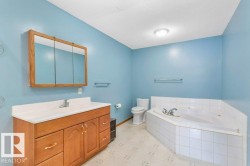 Bathroom featuring vanity, a bath, a textured ceiling, and light floors - 