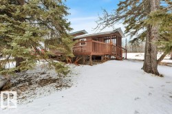 Snow covered rear of property with a deck and stairway - 