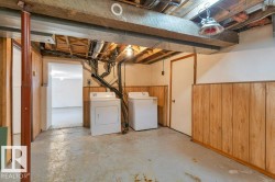 Unfinished below grade area featuring washer and clothes dryer and wooden walls - 