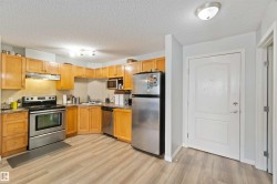 Kitchen with appliances with stainless steel finishes, a textured ceiling, under cabinet range hood, light wood-style floors, and tasteful backsplash - 