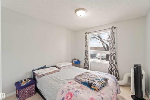 Carpeted bedroom with a textured ceiling - 2117 9357 Simpson Drive, Edmonton, AB - Indoor Photo Showing Bedroom