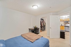 Bedroom with a textured ceiling, light colored carpet, and a spacious closet - 