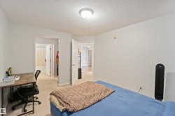 Bedroom featuring a textured ceiling, an office area, and light carpet - 