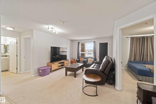 Living area featuring light colored carpet and a textured ceiling - 2117 9357 Simpson Drive, Edmonton, AB - Indoor Photo Showing Living Room