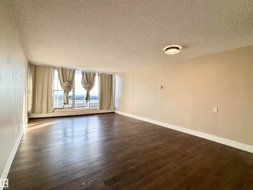 Unfurnished room featuring a textured ceiling and dark wood-type flooring - 133 8735 165 Street, Edmonton, AB - Indoor