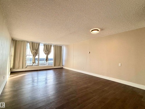 Unfurnished room with a textured ceiling, dark wood finished floors, and baseboard heating - 133 8735 165 Street, Edmonton, AB - Indoor Photo Showing Other Room