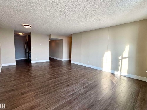 Unfurnished room with a textured ceiling and dark wood-style floors - 133 8735 165 Street, Edmonton, AB - Indoor