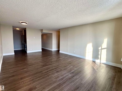 Unfurnished room featuring a textured ceiling and dark wood-style flooring - 133 8735 165 Street, Edmonton, AB - Indoor