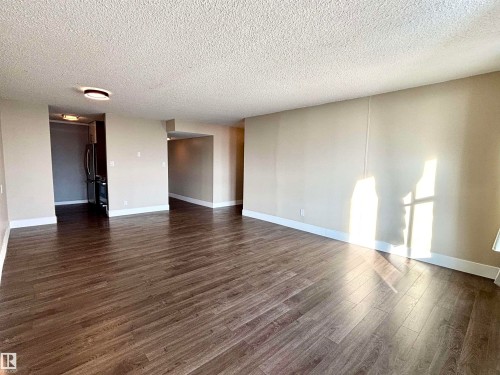 Empty room featuring a textured ceiling and dark wood-style floors - 133 8735 165 Street, Edmonton, AB - Indoor