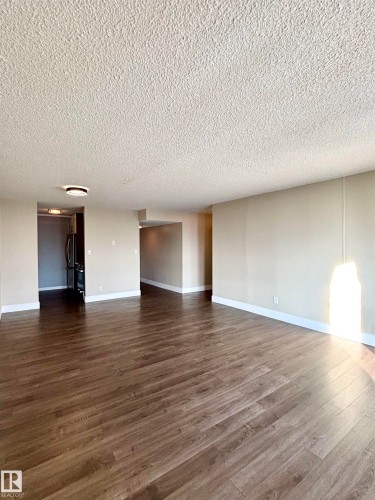 Unfurnished living room with a textured ceiling and dark wood-style floors - 133 8735 165 Street, Edmonton, AB - Indoor