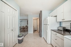 Kitchen with dark countertops, white cabinetry, freestanding refrigerator, light floors, and backsplash - 
