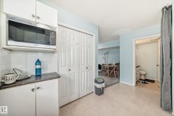 Kitchen featuring dark countertops, tasteful backsplash, white cabinets, and light floors - 