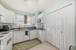 Kitchen featuring dark countertops, white appliances, white cabinets, light flooring, and decorative backsplash - 