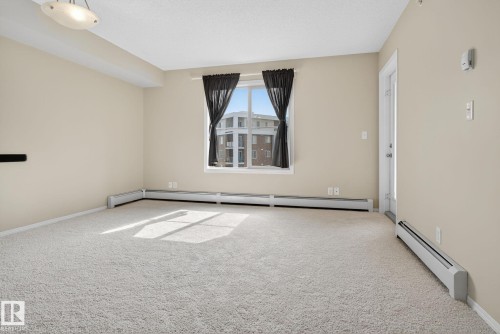 Unfurnished room featuring baseboard heating and carpet flooring - 414 12035 22 Avenue, Edmonton, AB - Indoor Photo Showing Other Room