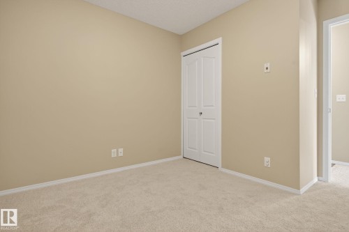 Unfurnished bedroom with light carpet, a closet, and a textured ceiling - 414 12035 22 Avenue, Edmonton, AB - Indoor Photo Showing Other Room