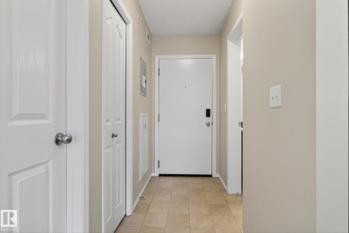 Hallway featuring a textured ceiling and light tile patterned floors - 414 12035 22 Avenue, Edmonton, AB - Indoor Photo Showing Other Room