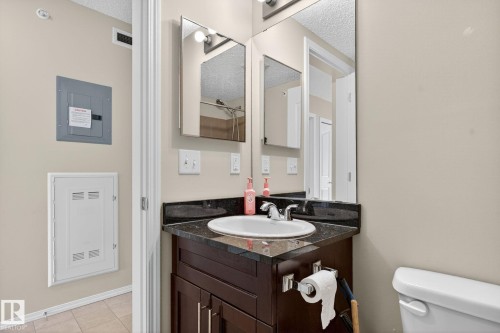 Half bath with vanity, electric panel, a textured ceiling, and light tile patterned floors - 414 12035 22 Avenue, Edmonton, AB - Indoor Photo Showing Bathroom