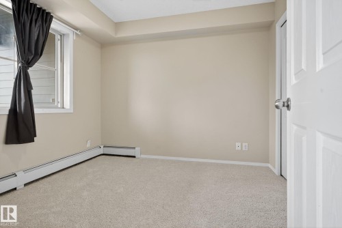 Empty room with light carpet and baseboards - 414 12035 22 Avenue, Edmonton, AB - Indoor Photo Showing Other Room
