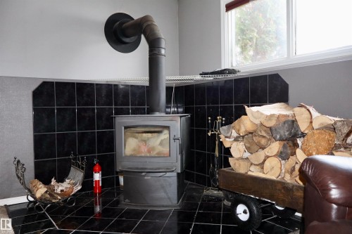 Detailed view of a wood stove and a fire extinguisher - 4505 58 Avenue, Barrhead, AB - Indoor